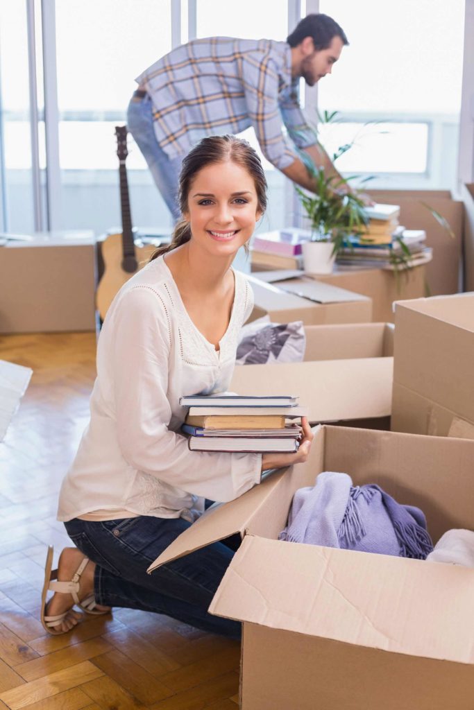 A woman holding books in her hands while sitting on the floor.