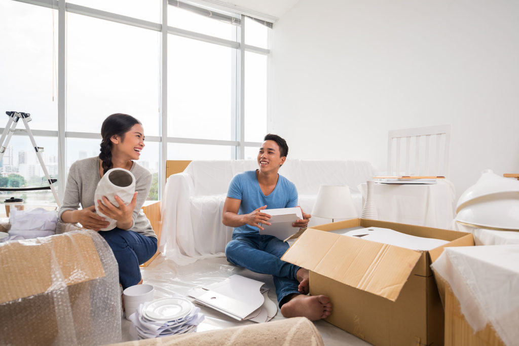 Two people sitting on a couch in front of boxes.